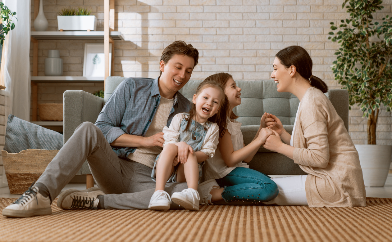 Happy family enjoying time together on cozy carpet flooring. Learn how to tell if you need new carpet on Carpet Master Carpet One's blog.