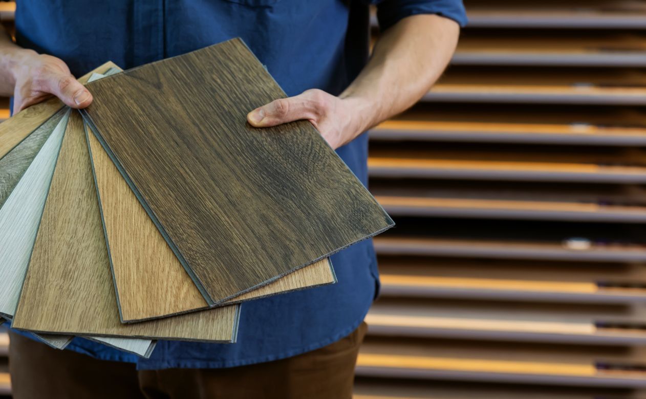 Man holding samples of waterproof wood-look luxury vinyl flooring, perfect for durable and stylish designs. Explore the best waterproof wood looks on Carpet Master Carpet One's blog.