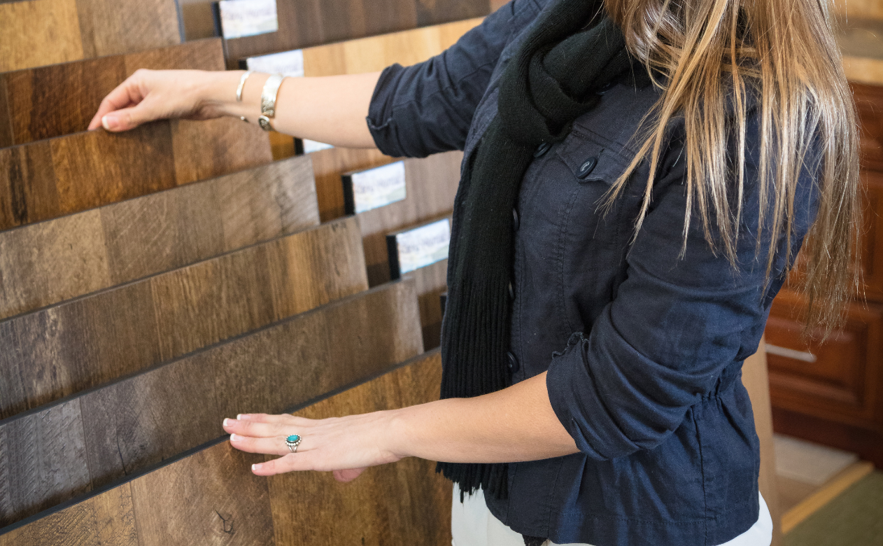 Customer exploring hardwood flooring options, featuring various wood species and finishes. Learn about the different hardwood species on Carpet Master Carpet One's blog.