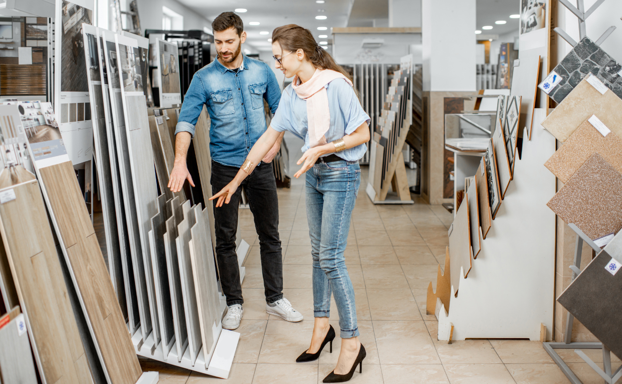 Customers exploring a variety of tile flooring options in a showroom. Learn about different types of tile at Carpet Master Carpet One's design blog.