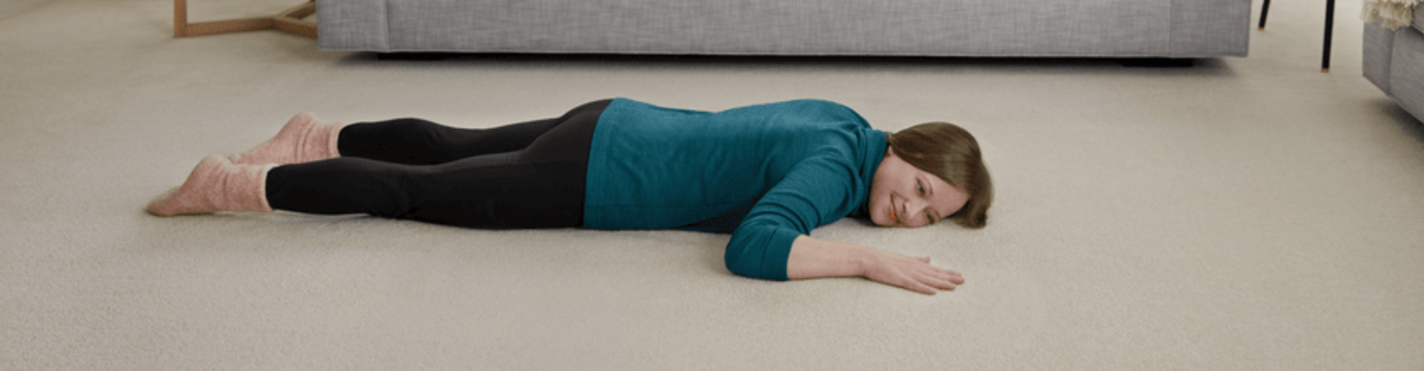 Woman enjoying plush carpet flooring in a cozy home. Explore soft, premium carpet options at Carpet Master Carpet One, your local flooring expert.